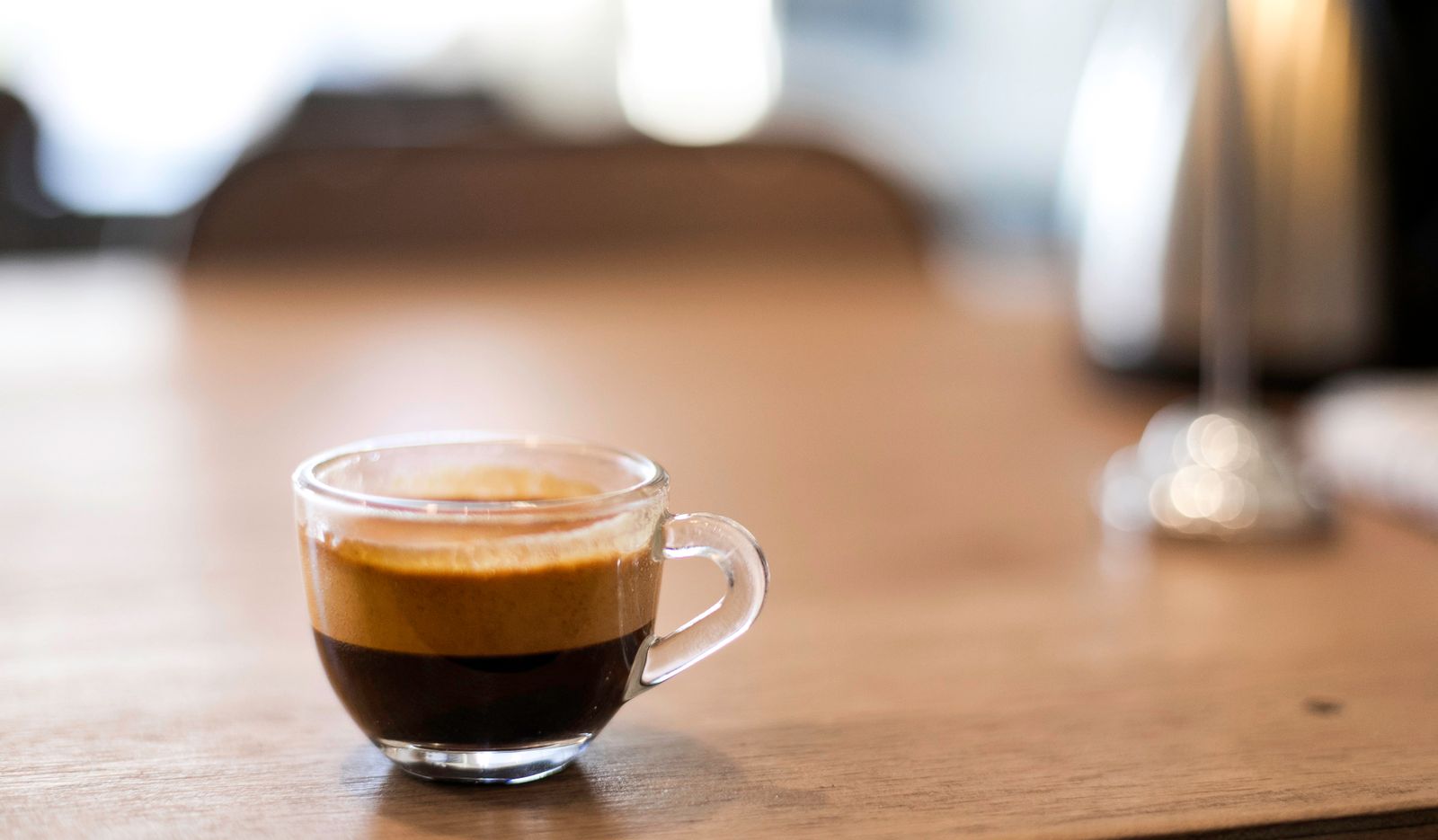 Ceasca de espresso cu crema aurie, pe o masa de lemn