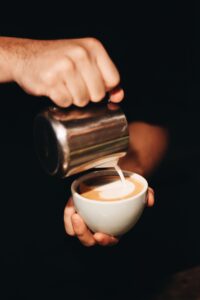 Barista toarna lapte spumat intr-o ceasca de cappuccino