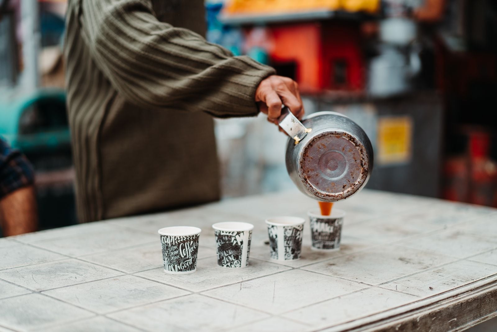 Cafea turnata dintr-un ibric metalic in pahare de carton
