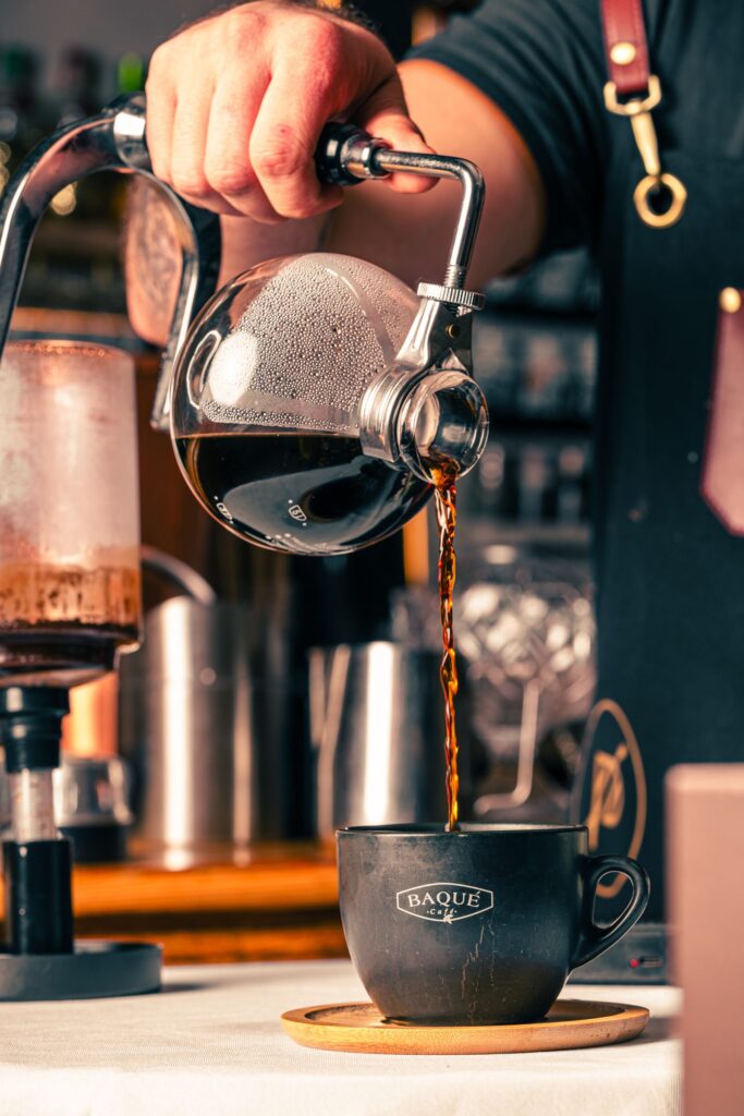 Barista toarna cafea neagra dintr-un syphon intr-o ceasca